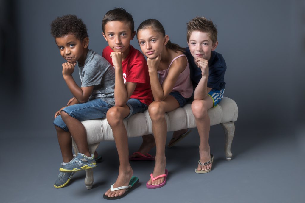 4 jeunes enfants, cousins, assis à la queue leu leu, tête reposant sur la main. Photo Studio Polidori