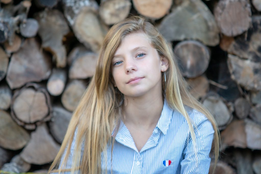 Une jeune fille pose devant des bûches, photo à domicile. Photo Studio Polidori