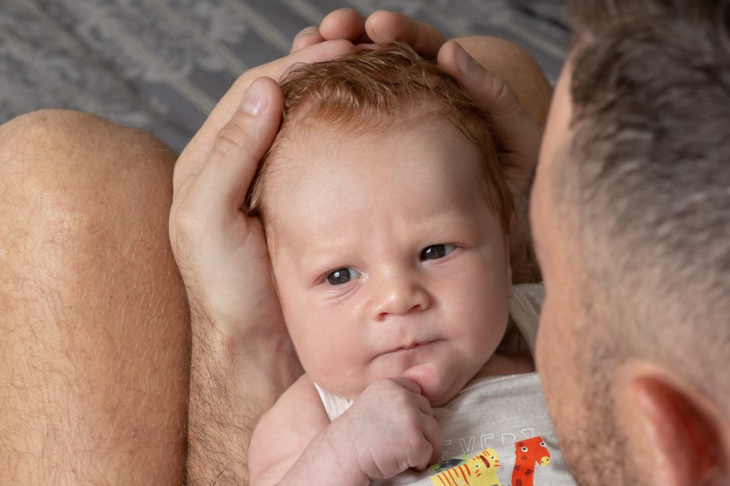 Beau regard d'un bébé dans les bras de son papa. Photo Studio Polidori