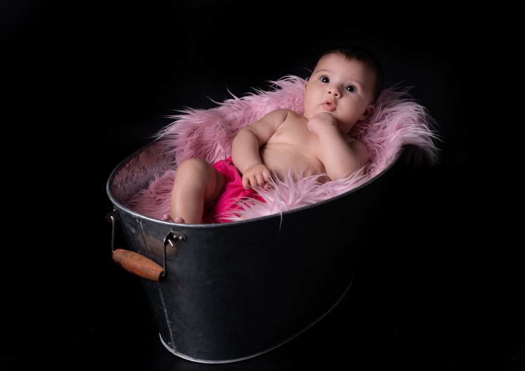 Le bébé nous regarde, allongé paisiblement dans une bassine en zinc et fourrure rose. Photo Studio Polidori