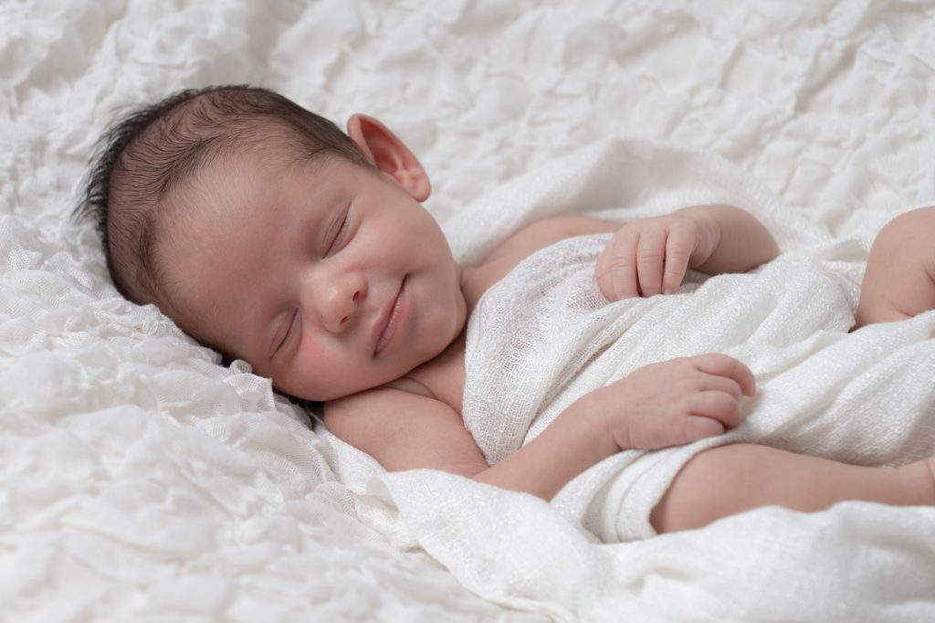Photo d'un bébé endormi sourire aux lèvres. Photo Studio Polidori