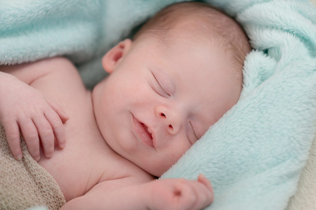 Bébé dormant paisiblement, sourire en coin. Photo Studio Polidori