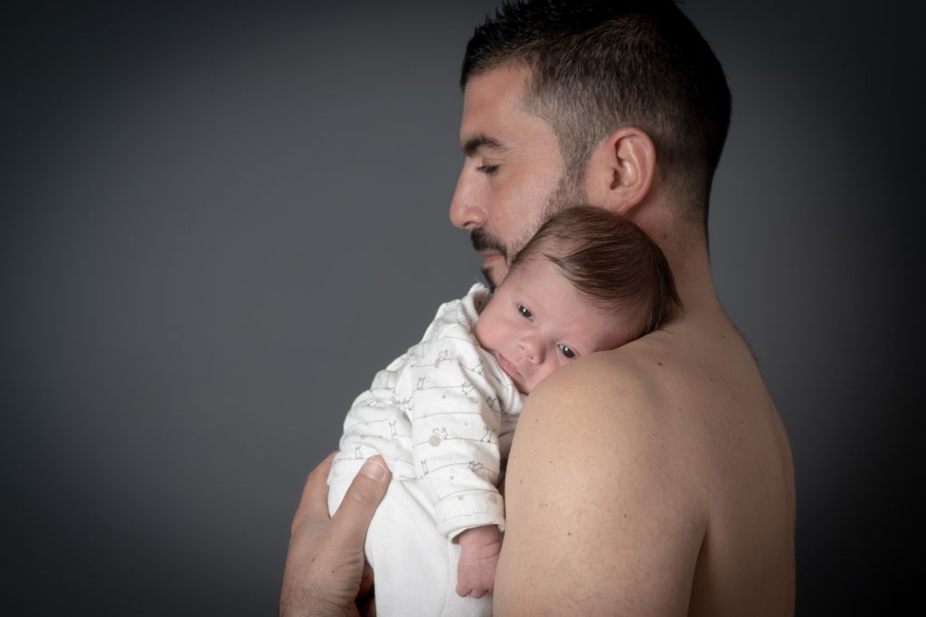 Bébé yeux grands ouverts, calé sur l'épaule de son papa. Photo Studio Polidori