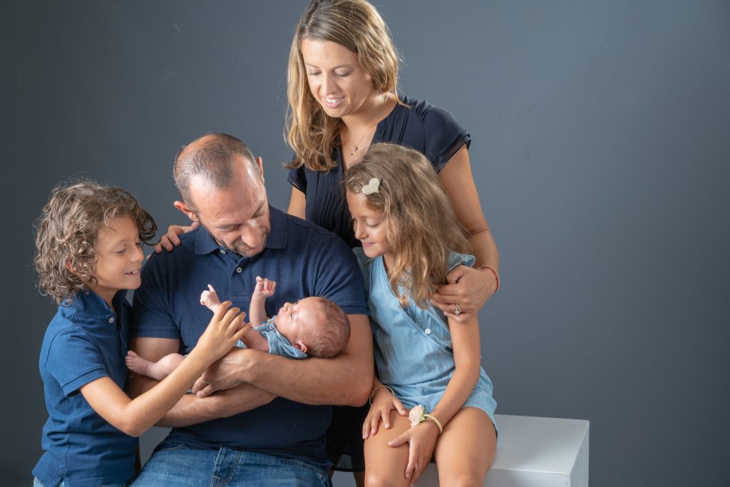 Une famille (maman, papa, 1 soeur et 1 frère) se retrouve autour de leur frère qui vient de naître. Photo Studio Polidori