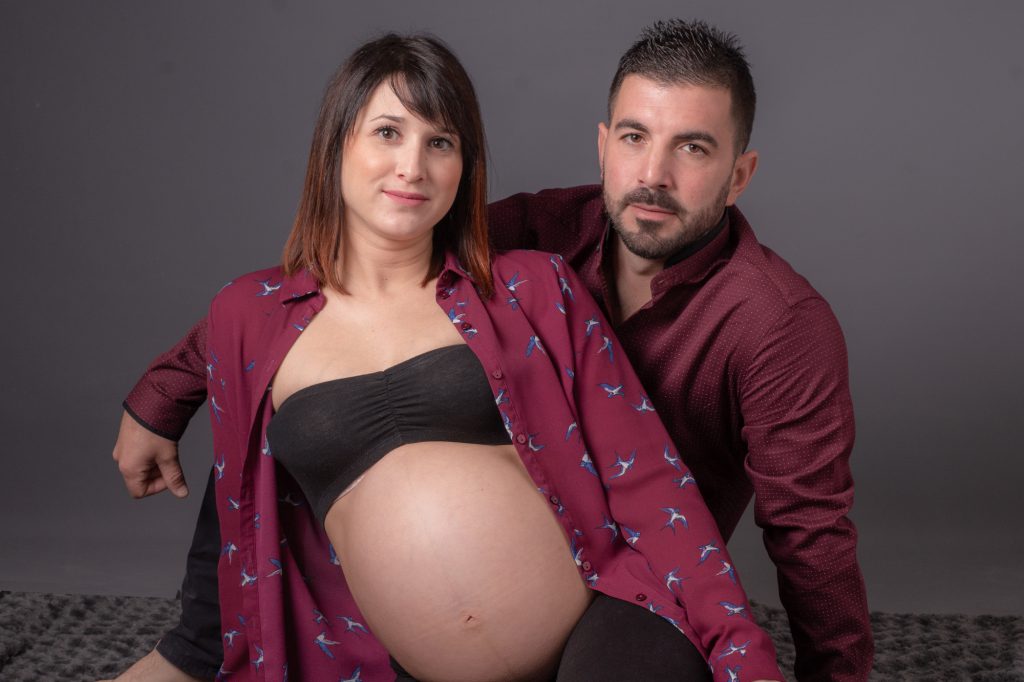 Femme enceinte et futur papa assis au sol. Photo Studio Polidori