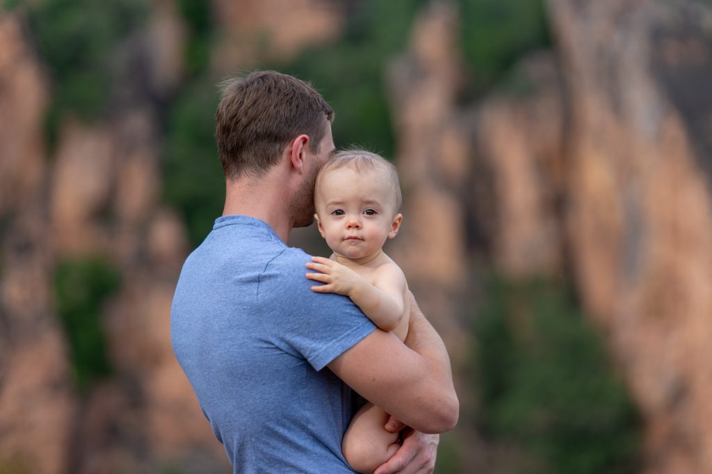 En pleine nature, un grand bébé au regard macieux , dans les bras de son papa. Photo Studio Polidori