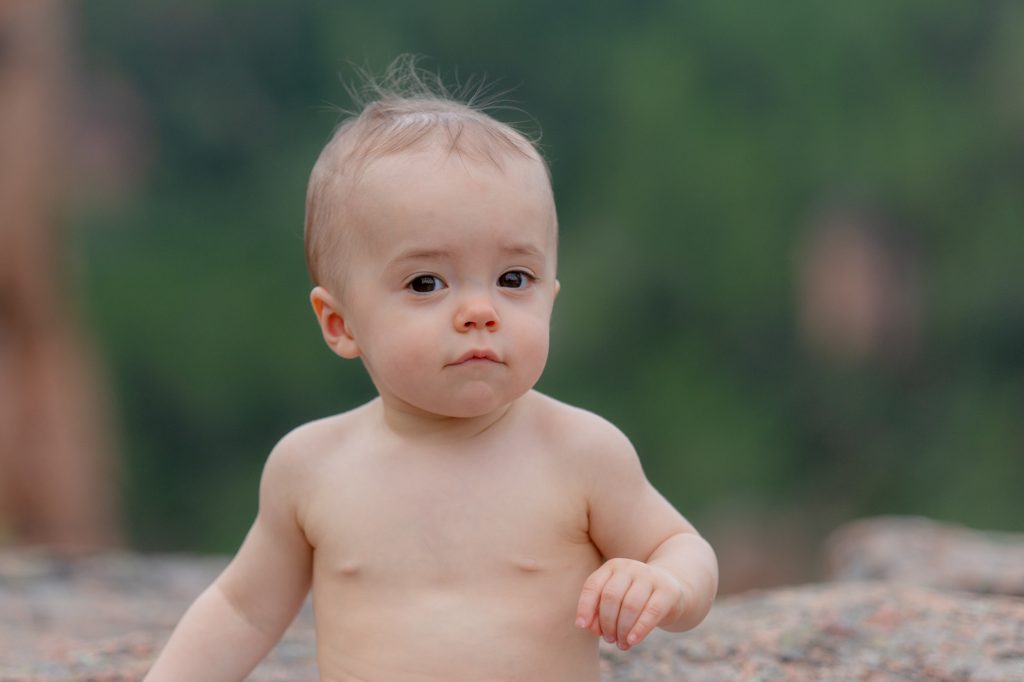 Un petit garçon, regard malicieux, torse nu, sur rocher à l'extérieur. Photo Studio Polidori