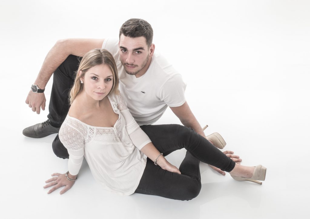 Un jeune couple assis en quinquonce, sur fond blanc. Photo Studio Polidori