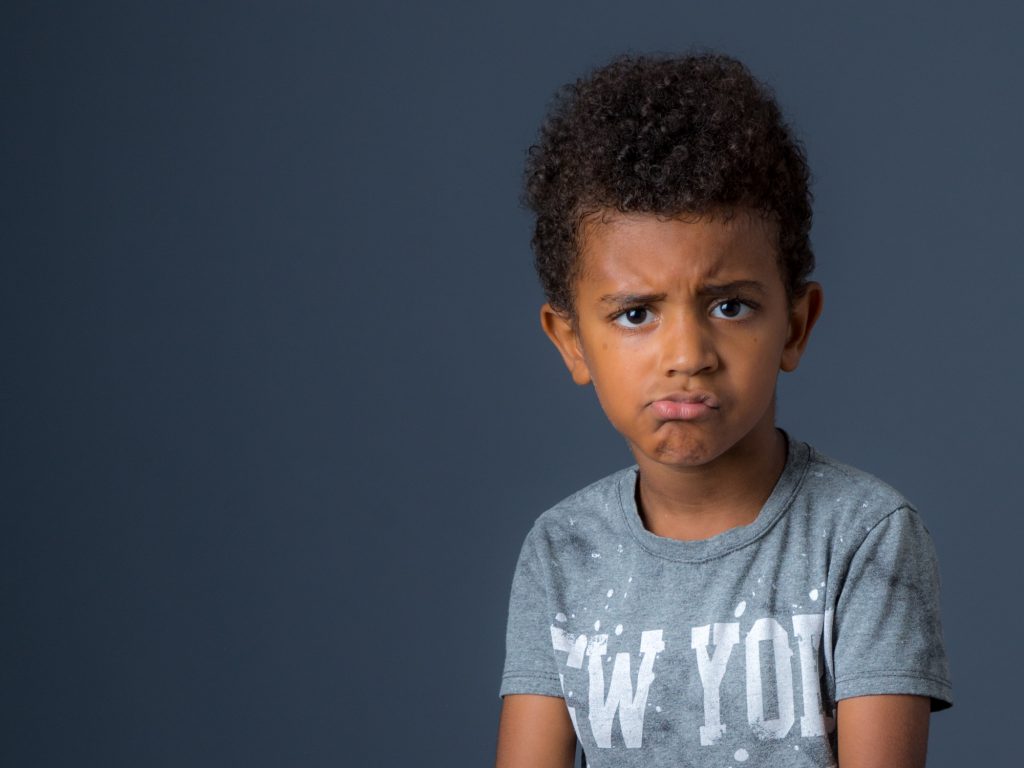 Un jeune garçon black pose au studio en grimaçant. Photo Studio Polidori