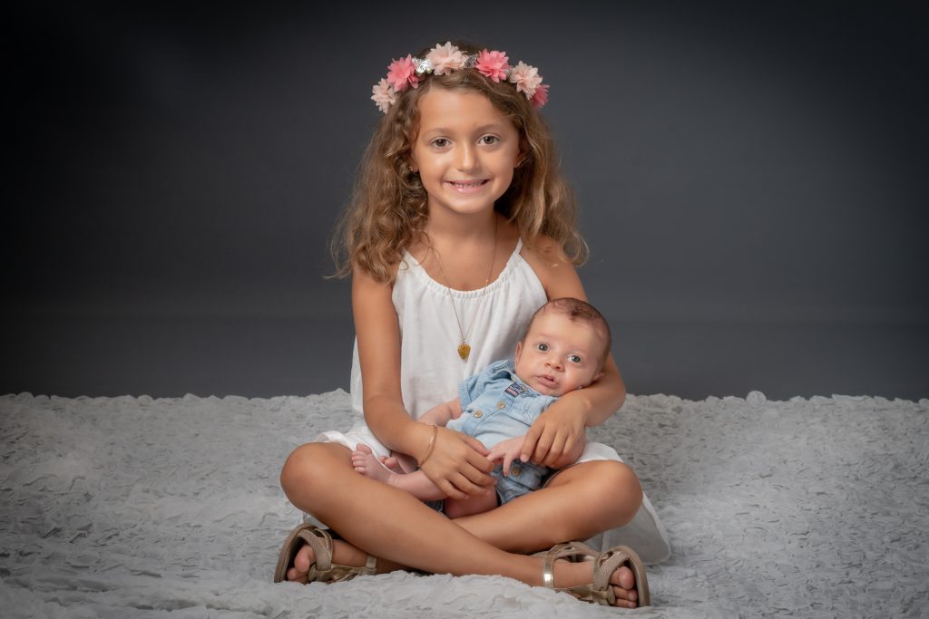 La grande soeur tient dans ses bras son petit frère, nouveau né. Photo Studio Polidori