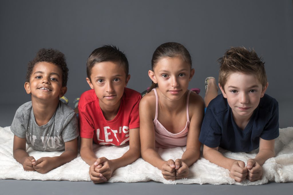 4 enfants, cousins, alignés au sol, en appui sur les coudes. Photo Studio Polidori