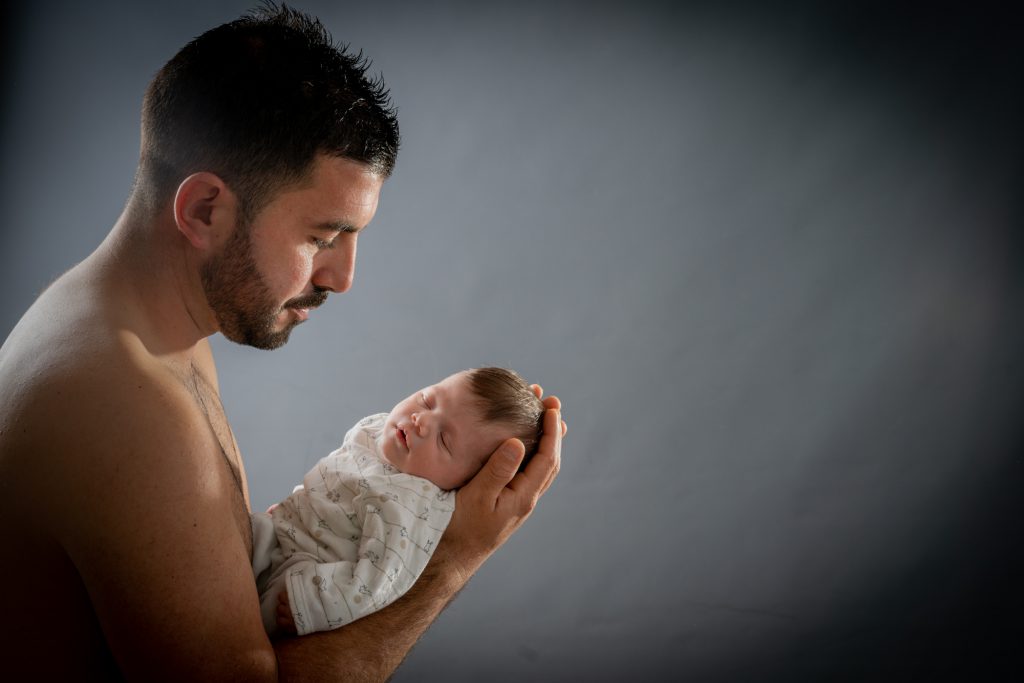 Regard tendre d'un papa envers son bébé, qui s'est endormi sur ses avant-bras. Photo Studio Polidori