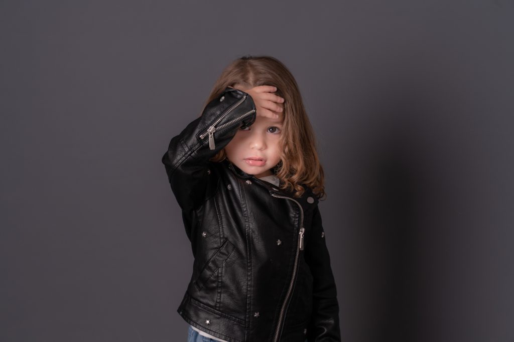 Une petite fille se tenant le front, dans son blouson de cuir. Photo Studio Polidori