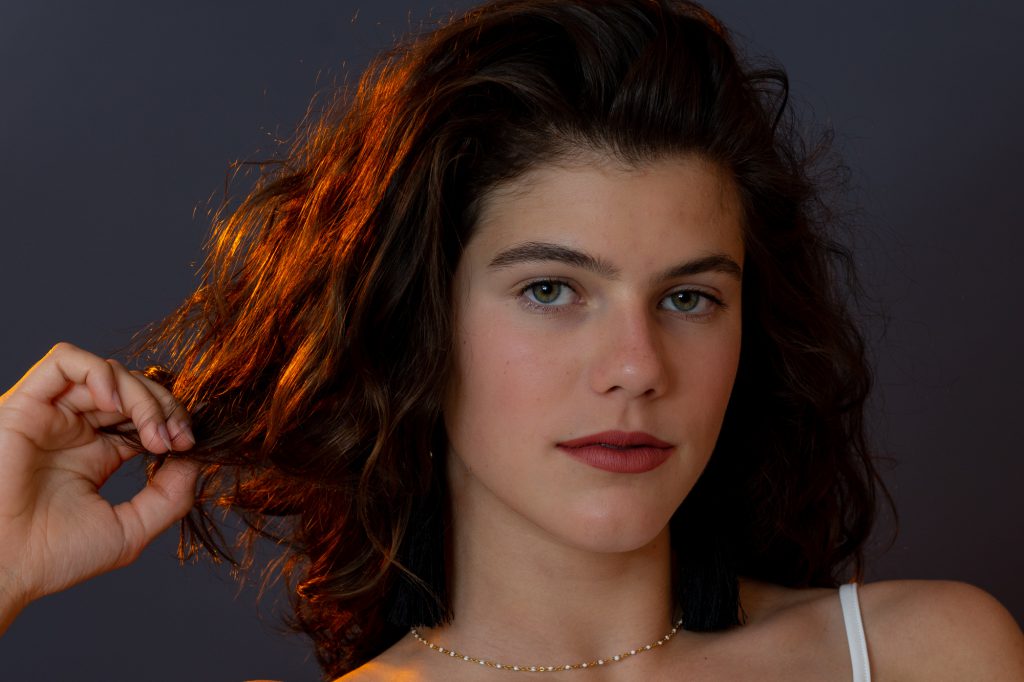 Portrait serré d'une jeune femme avec lumière retour orange. Photo Studio Polidori