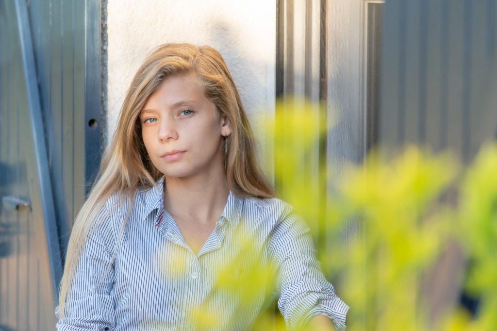 Une adolescente pose devant son domicile, découverte derrière végétation. Photo Studio Polidori