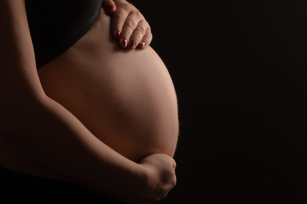 Ventre rond de future maman en profil, contre jour. Photo Studio Polidori