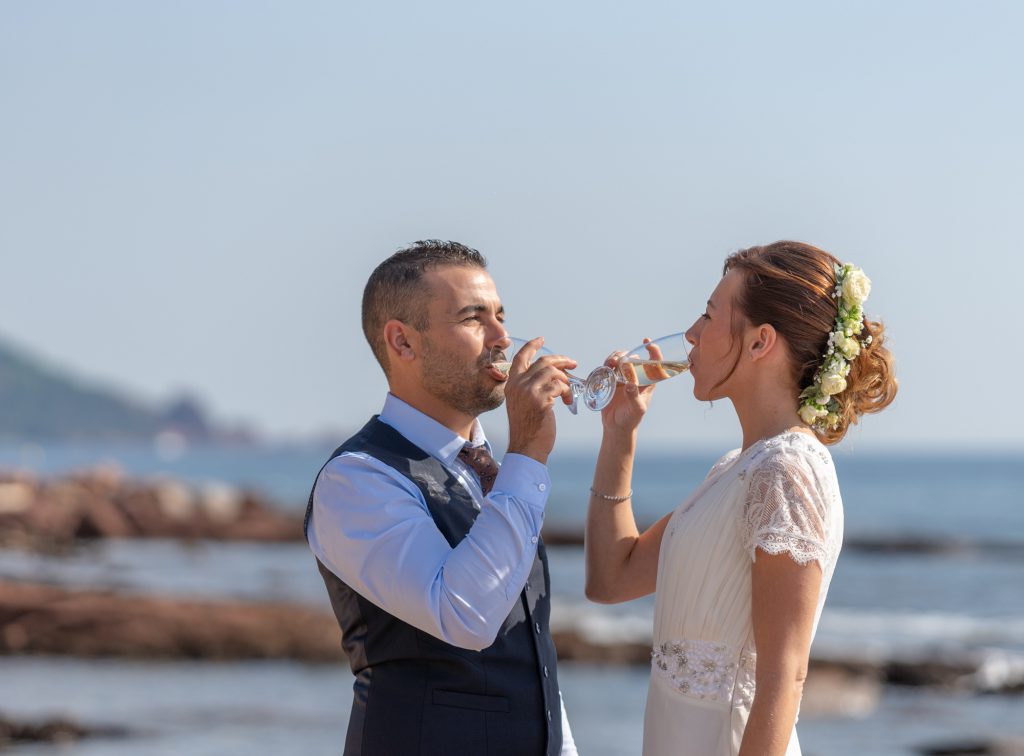 A la plage de Boulouris, les mariés partagent une coupe de champagen avec la mer en toile de fond. Photo Studio Polidori