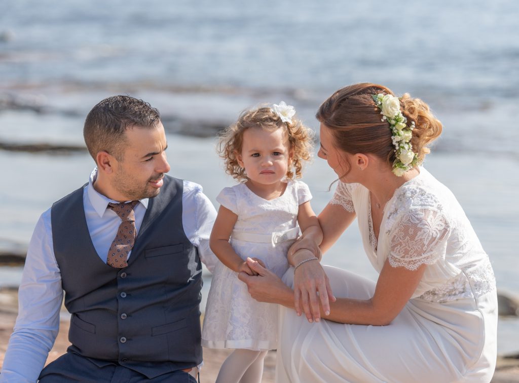 A la plage, les mariés regardent tendrement leur petite fille. A Boulouris. Photo Studio Polidori