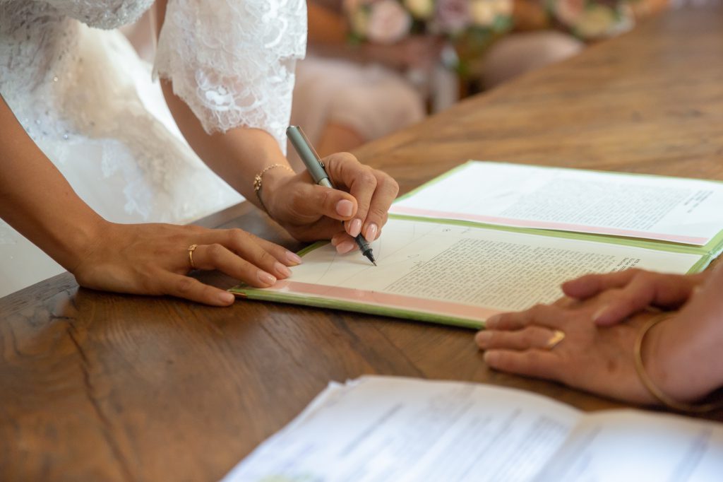 Main de la mariée signant l'acte de mariage. Photo Studio Polidori